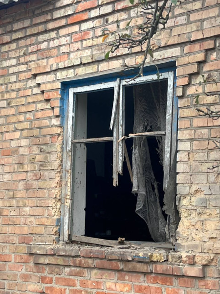 Вибите вікно з пошкодженою дерев'яною рамою та порваною фіранкою в будинку села Мар'янське Криворізького району після російських атак