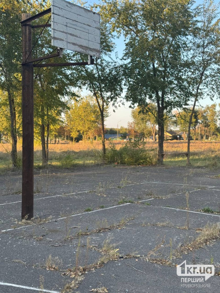 Занедбаний спортивний майданчик без баскетбольних кілець із потрісканим асфальтом та бур'янами у Довгинцівському районі Кривого Рогу