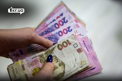 Человек держит в руках украинские гривны разного номинала