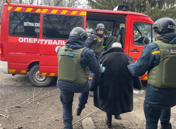 Спасатели ГСЧС помогают женщине сесть в автомобиль психологической помощи