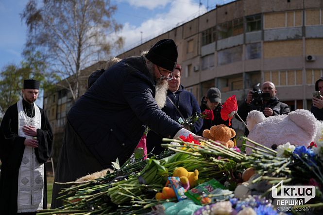 священники кладут цветы и игрушки на мемориал кривой рог