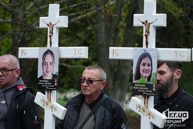 У Радушному Криворізького району чоловіки тримають білі похоронні хрести з фотографіями двох дівчат, які загинули внаслідок російської атаки 30 липня.