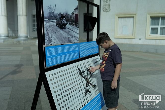 Дитина розглядає пошкоджений дрон на виставці «Гуманітарна система під ударом» у Кривому Розі